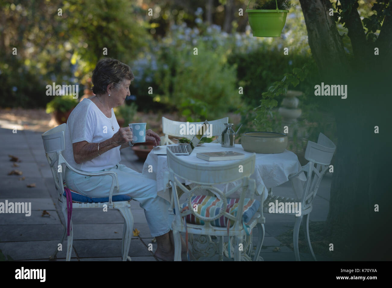 Senior donna utilizzando computer portatile mentre un caffè in giardino Foto Stock