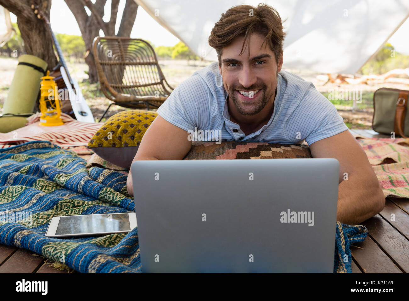 Ritratto di giovane sorridente uomo utilizzando laptop in tenda Foto Stock