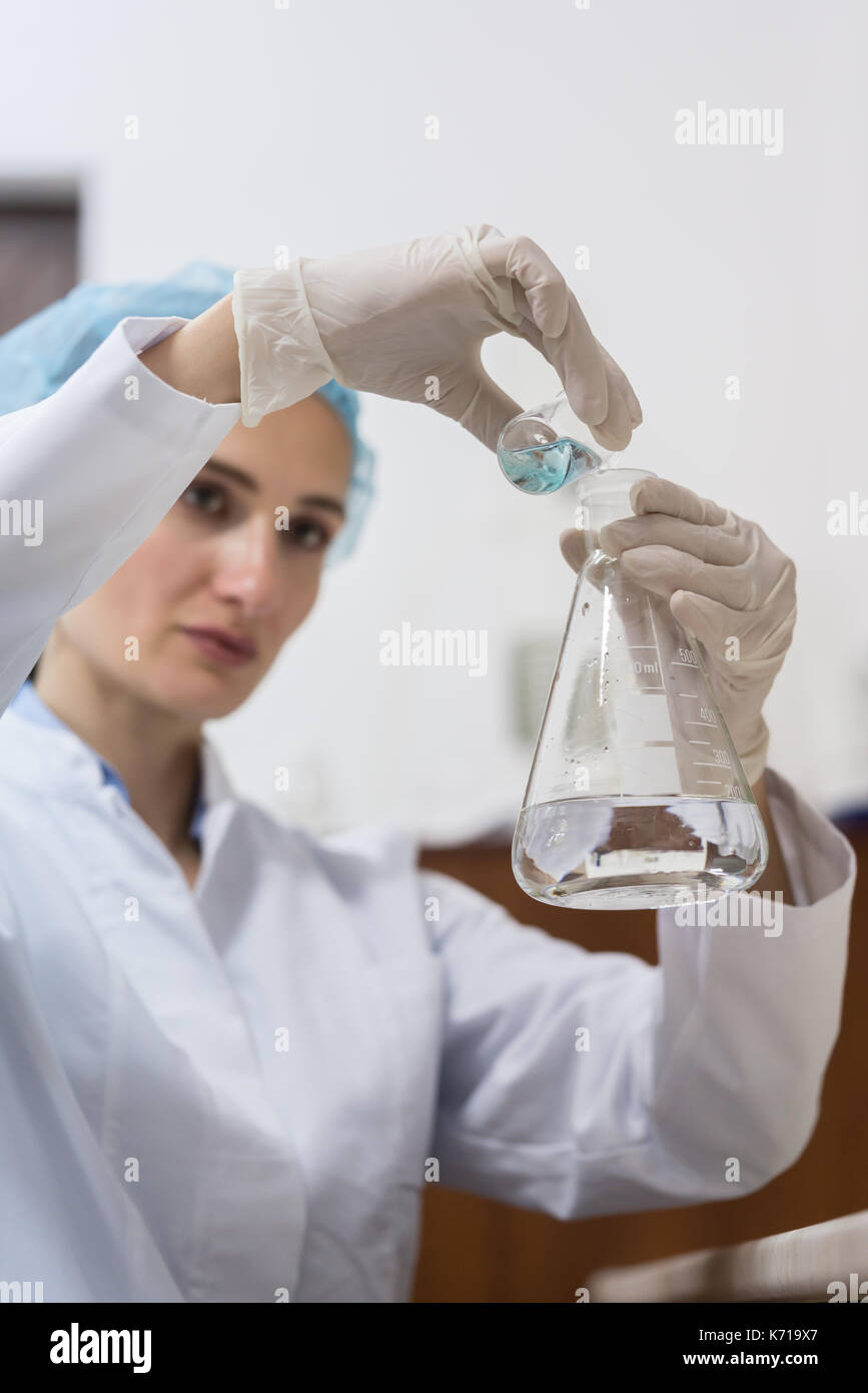 Il farmacista la miscelazione di due sostanze chimiche liquide durante l'esperimento Foto Stock