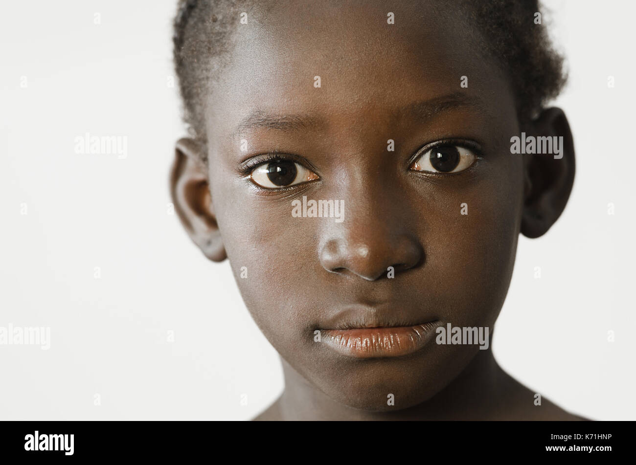 Triste bambino africano che mostra il suo volto per un ritratto, tristezza disperazione simbolo, isolato su bianco Foto Stock