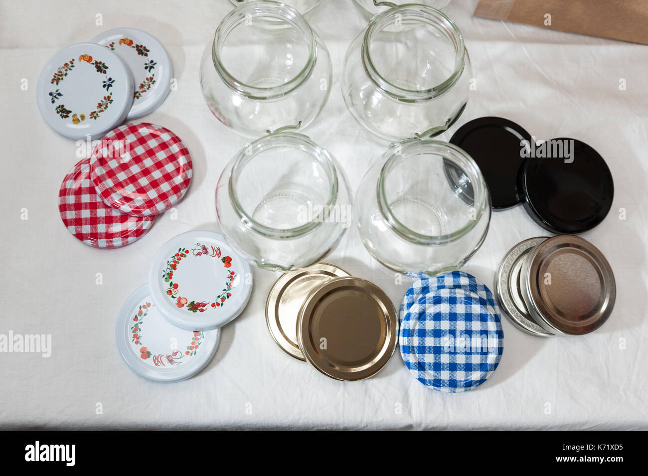 Una raccolta di vetro vasi di marmellata e coperchi su un tavolo bianco panno. Foto Stock