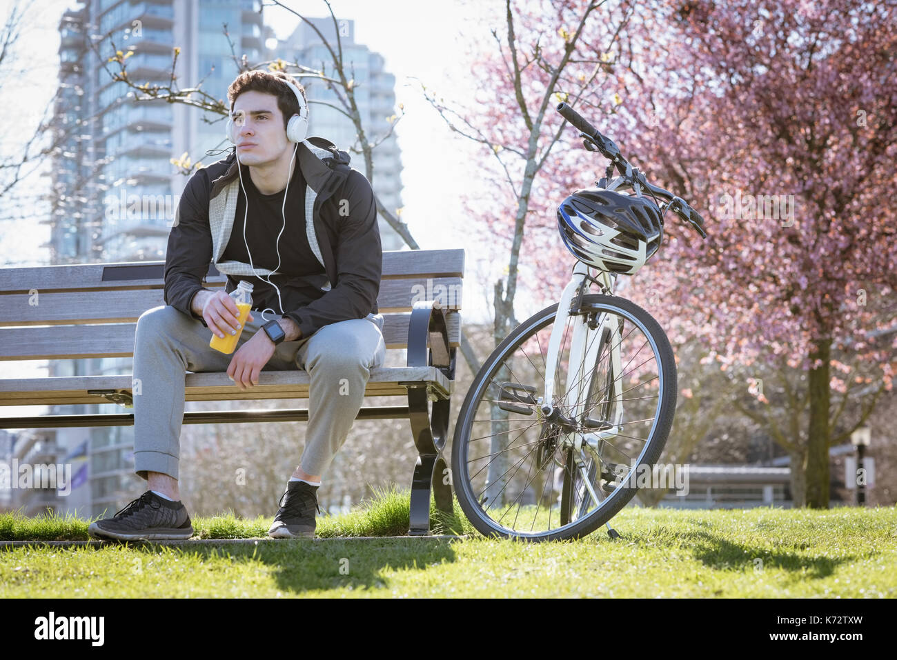 Lunghezza completa di uomo che guarda lontano mentre si ascolta la musica al parco Foto Stock