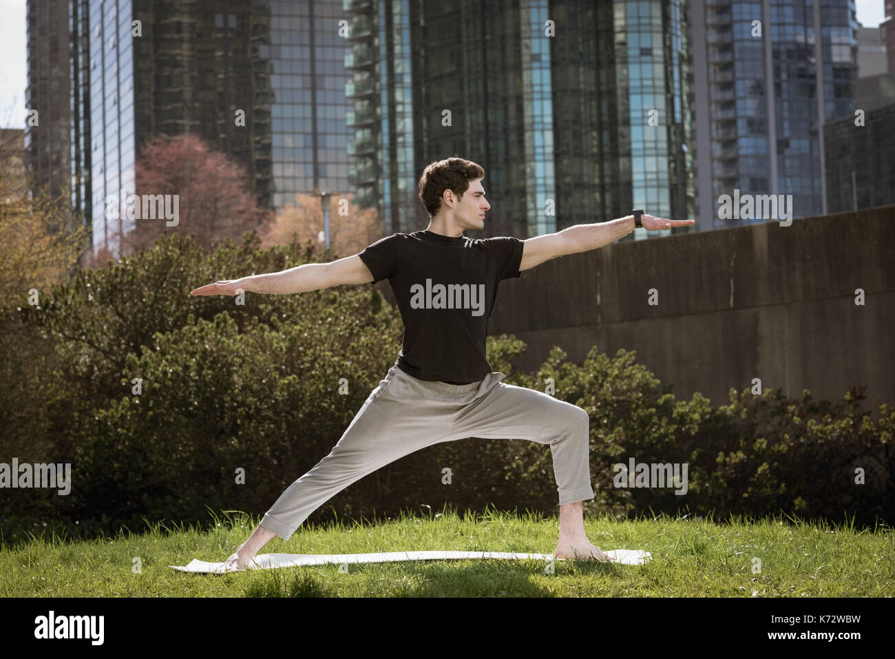 Per tutta la lunghezza della giovane guerriero facendo 2 pongono yoga in campo al park Foto Stock