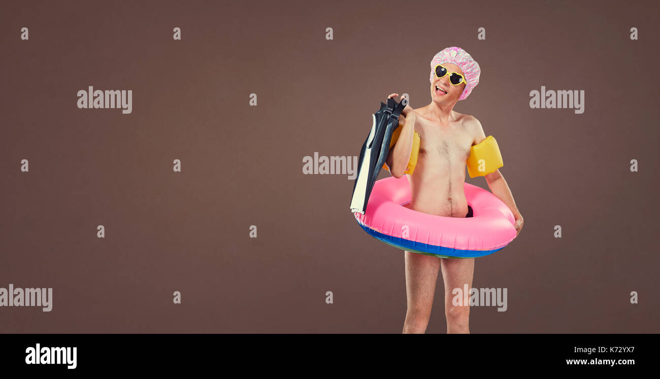 Divertente allegro uomo sottile in un costume da bagno con un gonfiabile cir Foto Stock