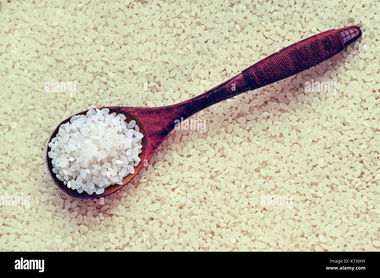 Pulire il riso in bianco in un cucchiaio di legno su uno sfondo di colore giallo. Riso Riso a grani tondi Foto Stock