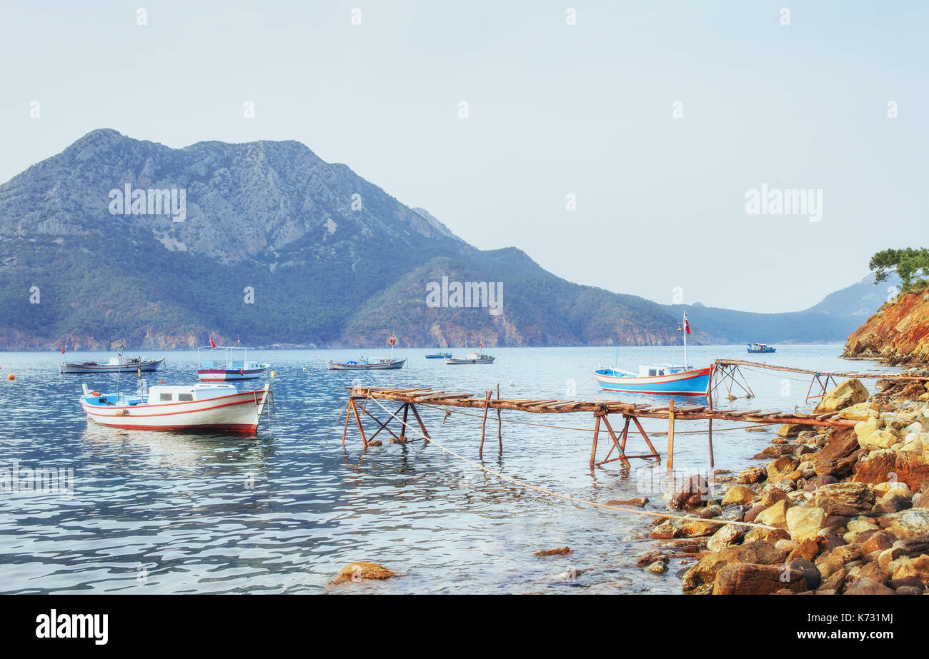 Barche vicino al molo rotto, mettendo in una quiete serena blu acqua di mare Foto Stock