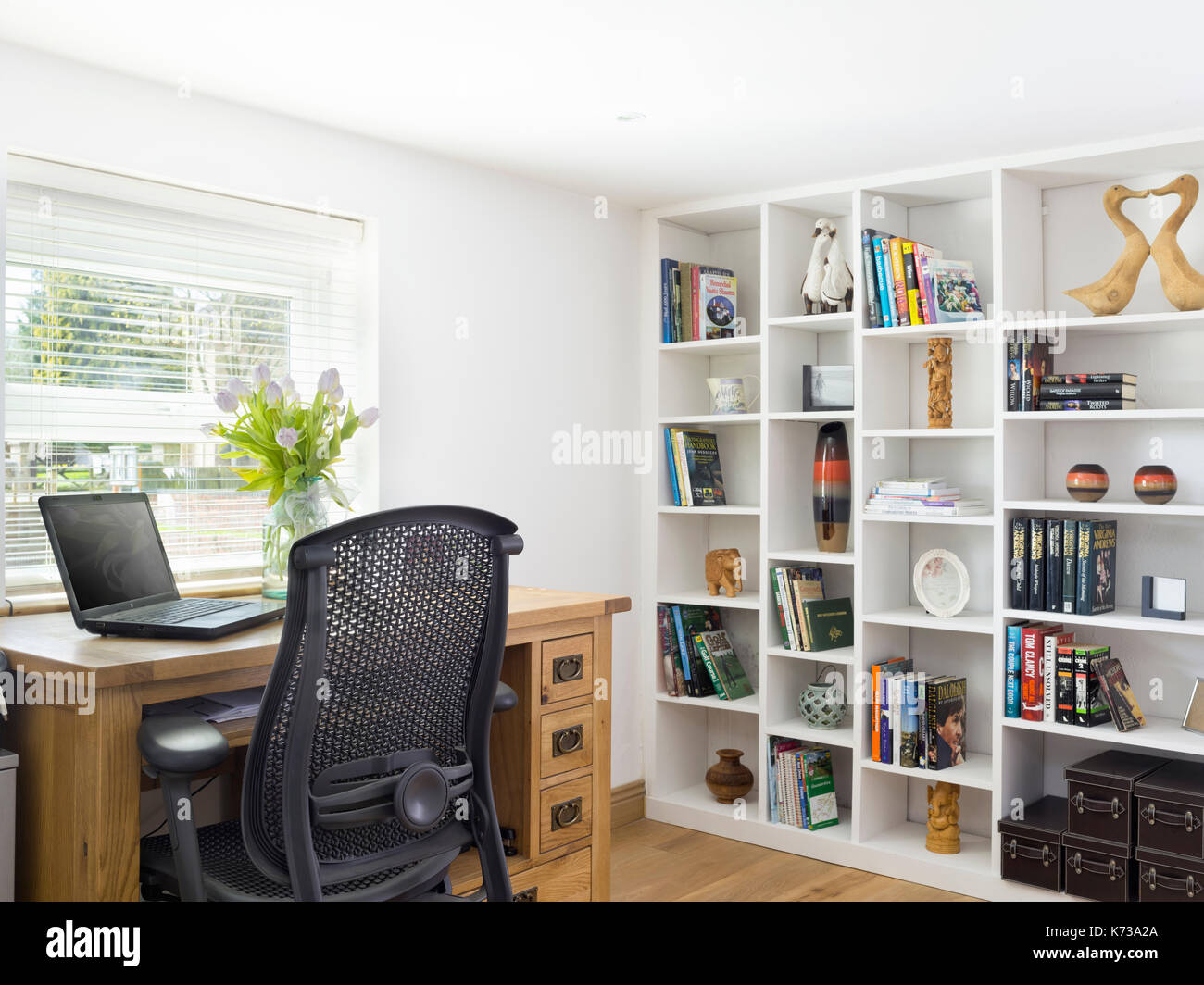 Un piacevole casa ufficio in una casa moderna con scrivania in legno di quercia, laptop e scaffali Foto Stock
