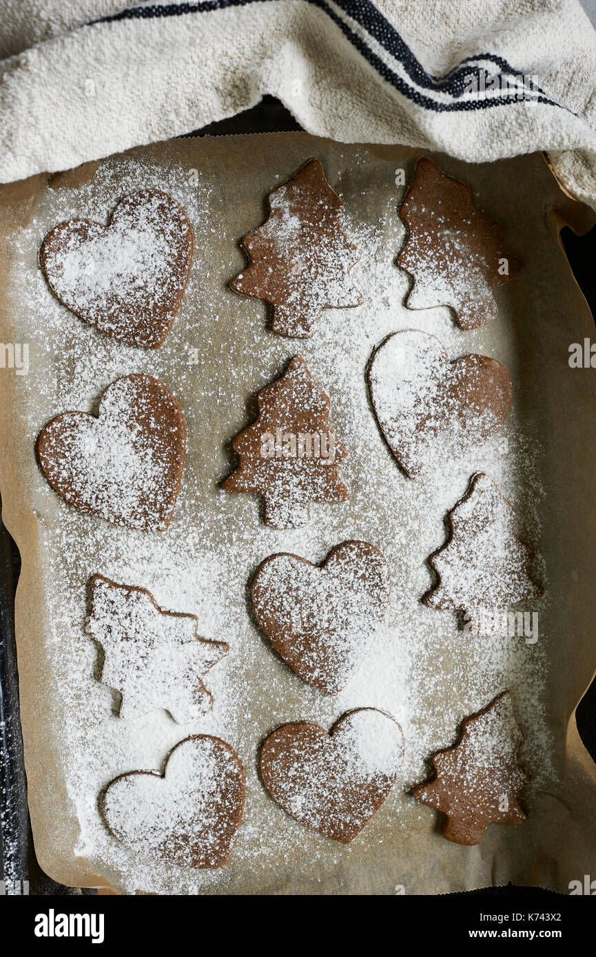 Cucina foto di una spolverata tagliere di legno ed anticato t-asciugamano con crudo, preparati, pasta biscotto tagliate in forme di festa per il natale. Foto Stock