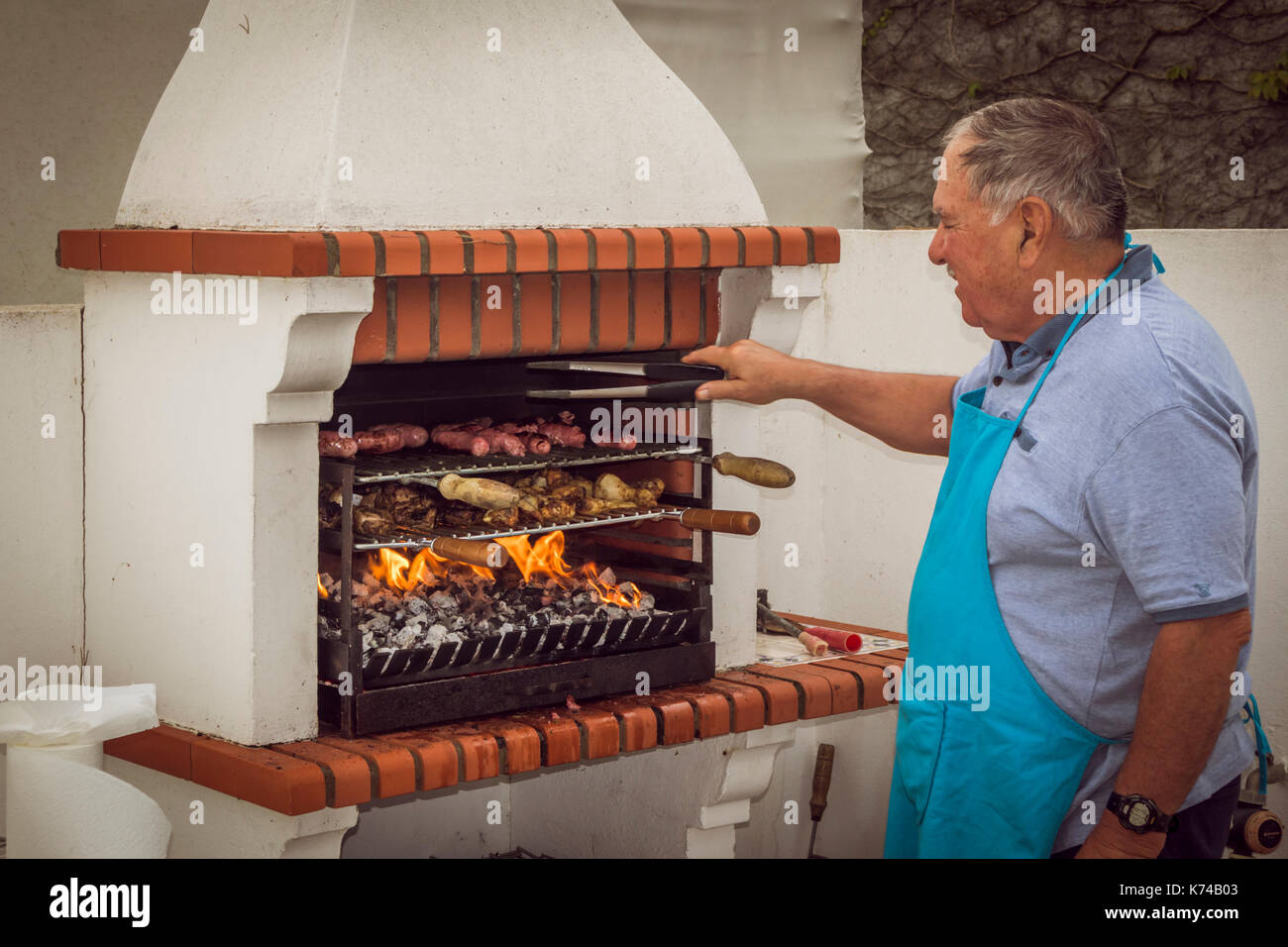 L'uomo tende al cibo che alla griglia su un portoghese barbecue a carbone. Portogallo Foto Stock