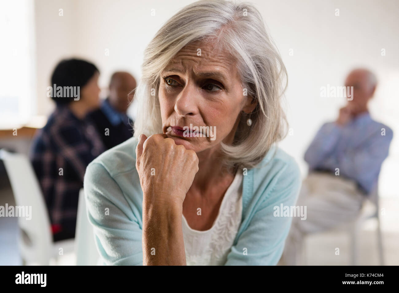 Tensionata senior femmina con amici in background in classe d'arte Foto Stock