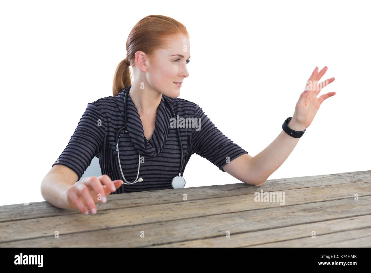 Medico donna toccando lo schermo immaginario a tavola contro backgroound bianco Foto Stock