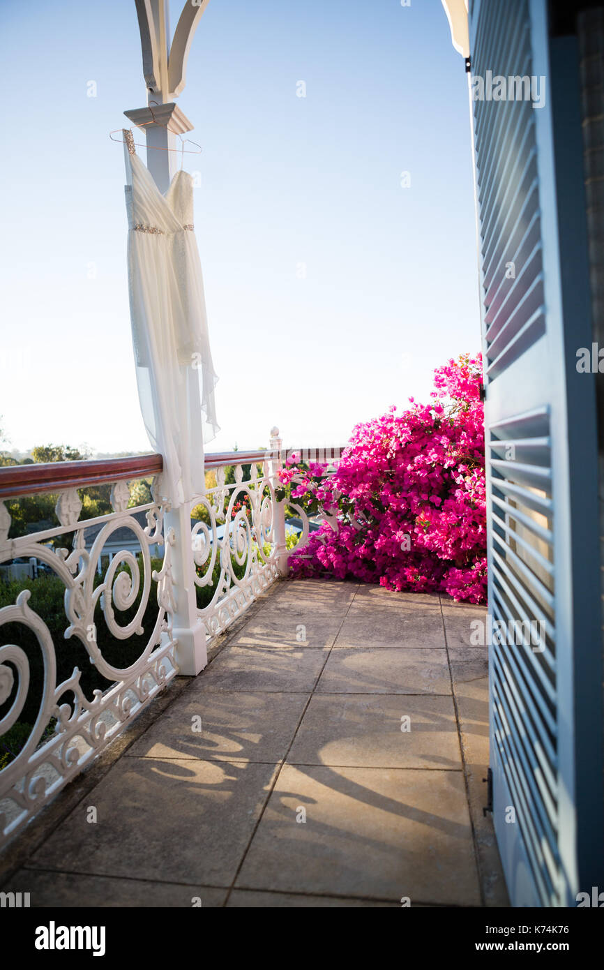 Abito da sposa appeso su colonna architettonica in balcone Foto Stock