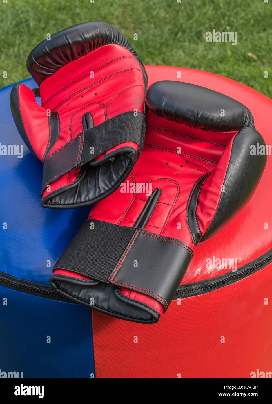 Una coppia di morbida e imbottita, sparring protettivo guanti in appoggio su un punchbag dopo un kickboxing allenamento fitness. Ogni guanto è nero e rosso. Foto Stock