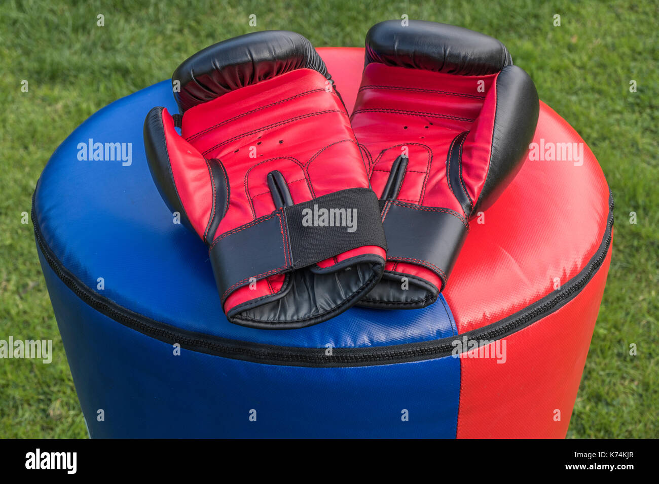 Una coppia di morbida e imbottita, sparring protettivo guanti in appoggio su un punchbag dopo un kickboxing allenamento fitness. Ogni guanto è nero e rosso. Foto Stock