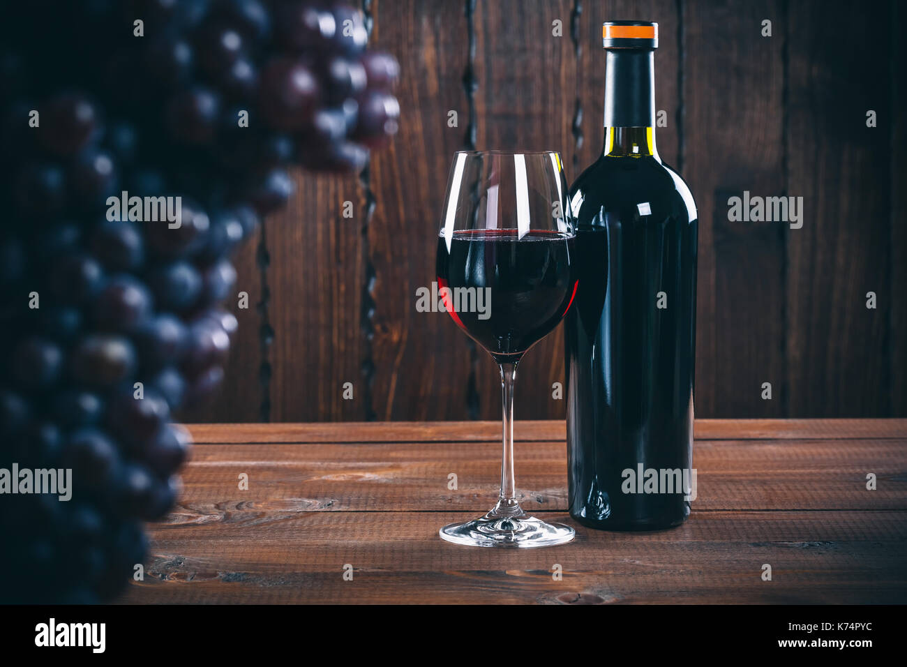 Bottiglia e bicchiere di vino rosso, uva e sughero su sfondo di legno. Foto Stock