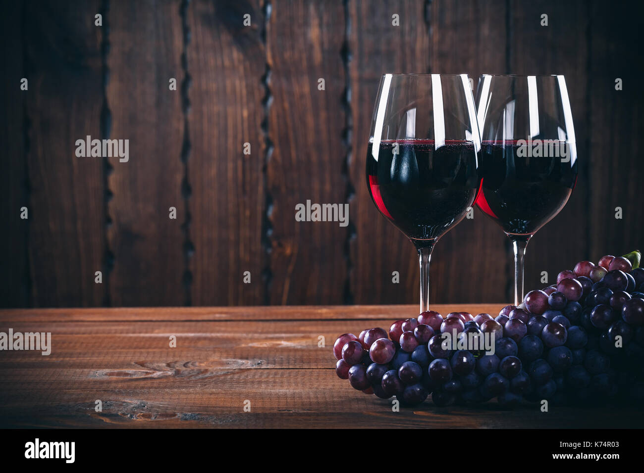 Due vino bicchiere di vino rosso e Uva su sfondo di legno. Foto Stock