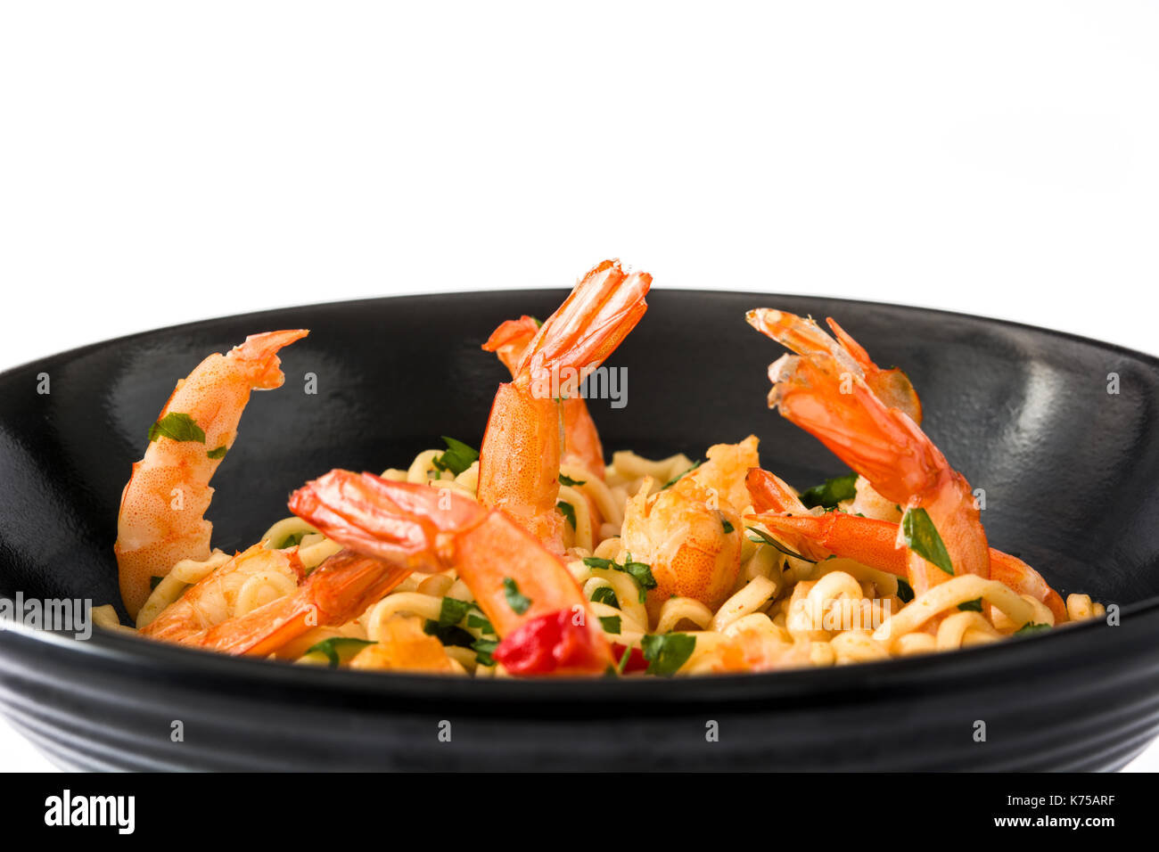 Tagliatelle e gamberetti con verdure in vaso nero isolato Foto Stock