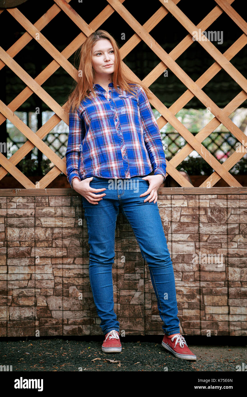 Ritratto di una bella ragazza. Sorridendo, ponendo sulla fotocamera. in una maglietta blu in una gabbia. Sullo sfondo di legno griglia a griglia. Foto Stock