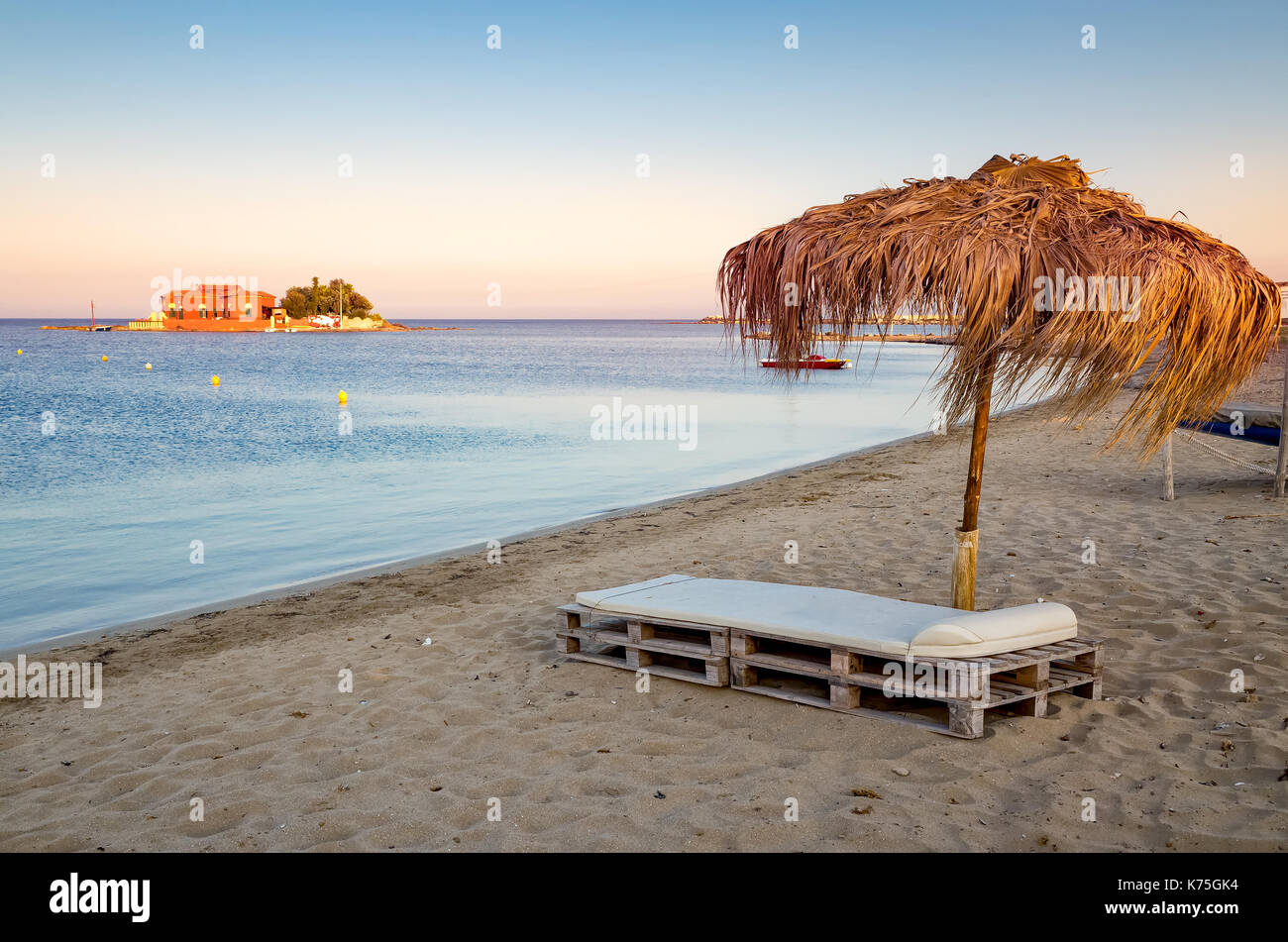 Un bellissimo angolo remoto del paradiso. Il mare turchese, un deckbed, sabbia dorata e ombrello. Marzamemi, Sicilia, Italia Foto Stock