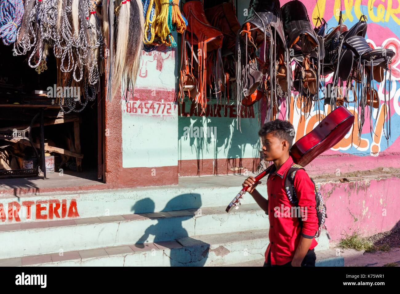 Nicaragua, Esteli provincia, Esteli, uomo con una chitarra prima di un negozio di vendita di funi e selle di cavallo Foto Stock