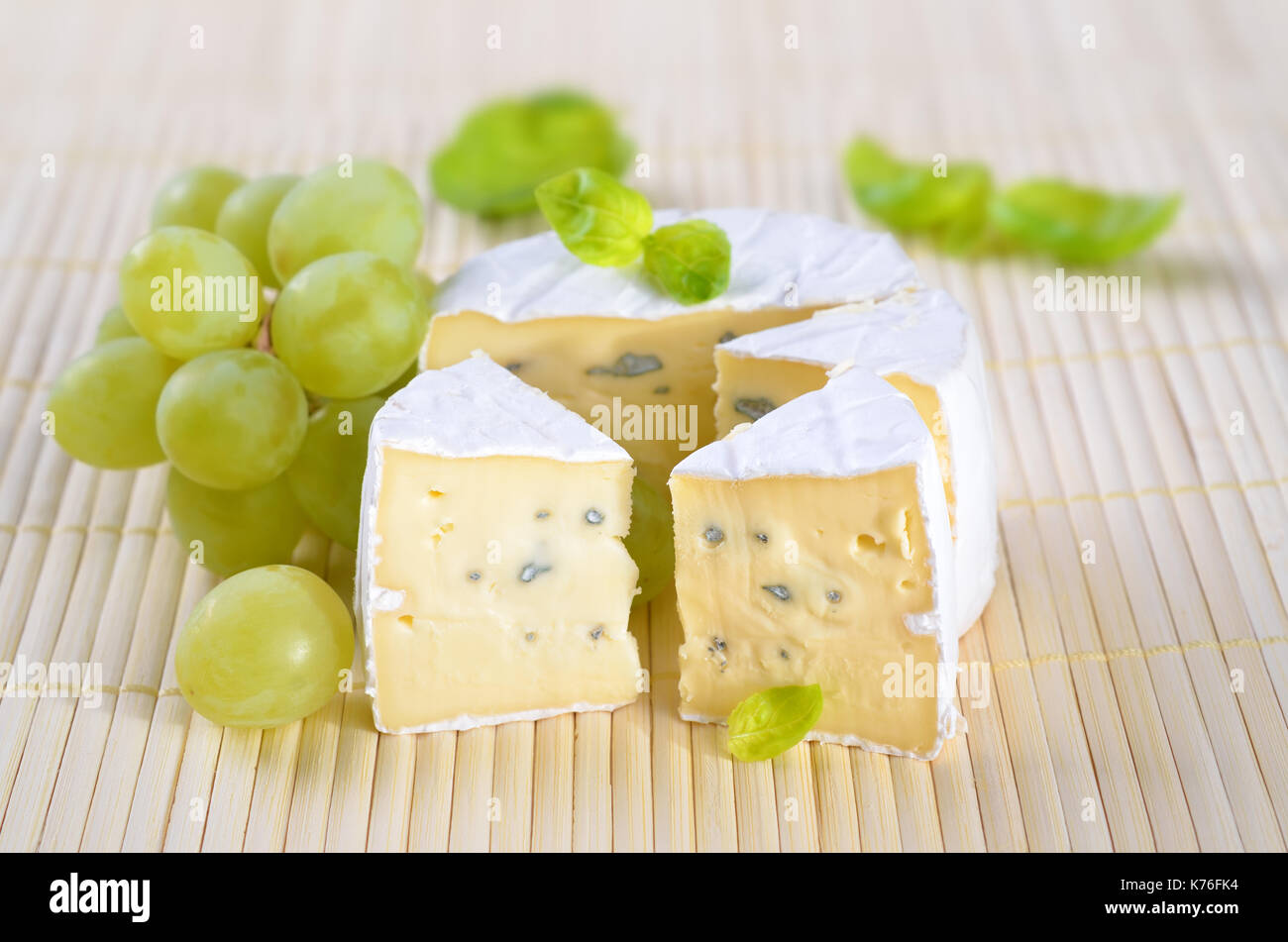 Il francese camembert formaggio a pasta morbida con uve e marjorjam su un cartellone di legno Foto Stock