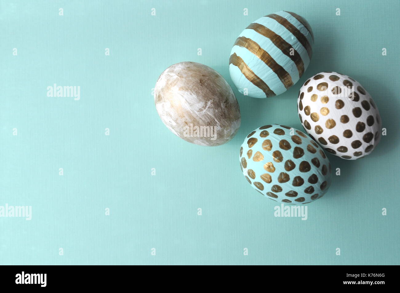 Decorate le uova di pasqua con motivi floreali notebook e la tazza di tè alla menta su aqua teal blu sfondo turchese con spazio di copia Foto Stock