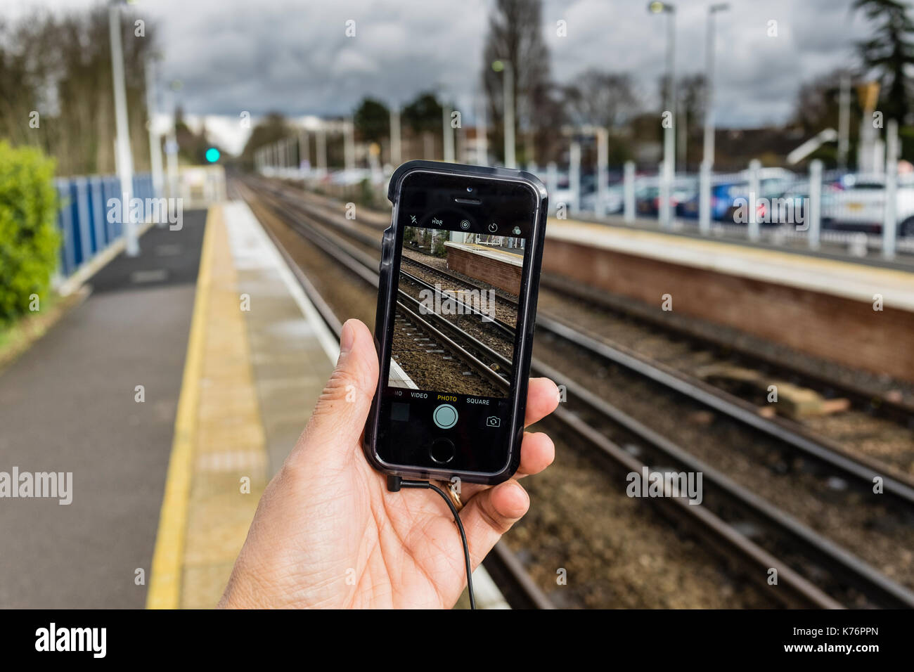 Un maschio di scattare le foto del binario ferroviario con un iPhone se lo smartphone, REGNO UNITO Foto Stock