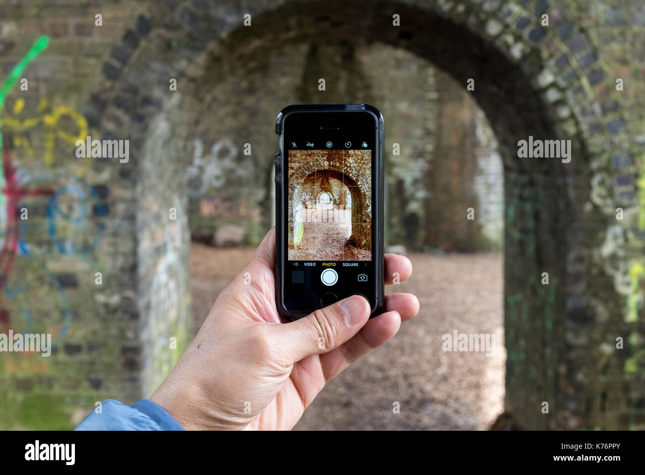 Un maschio per scattare delle foto di un viadotto ferroviario con un iPhone se lo smartphone, REGNO UNITO Foto Stock