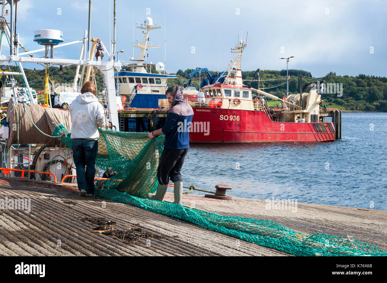Killybegs, County Donegal, Irlanda. I pescatori in Irlanda il premier pesca porto approfittare di qualche raggio di sole per asciugare le reti da pesca sulla quaysi Foto Stock
