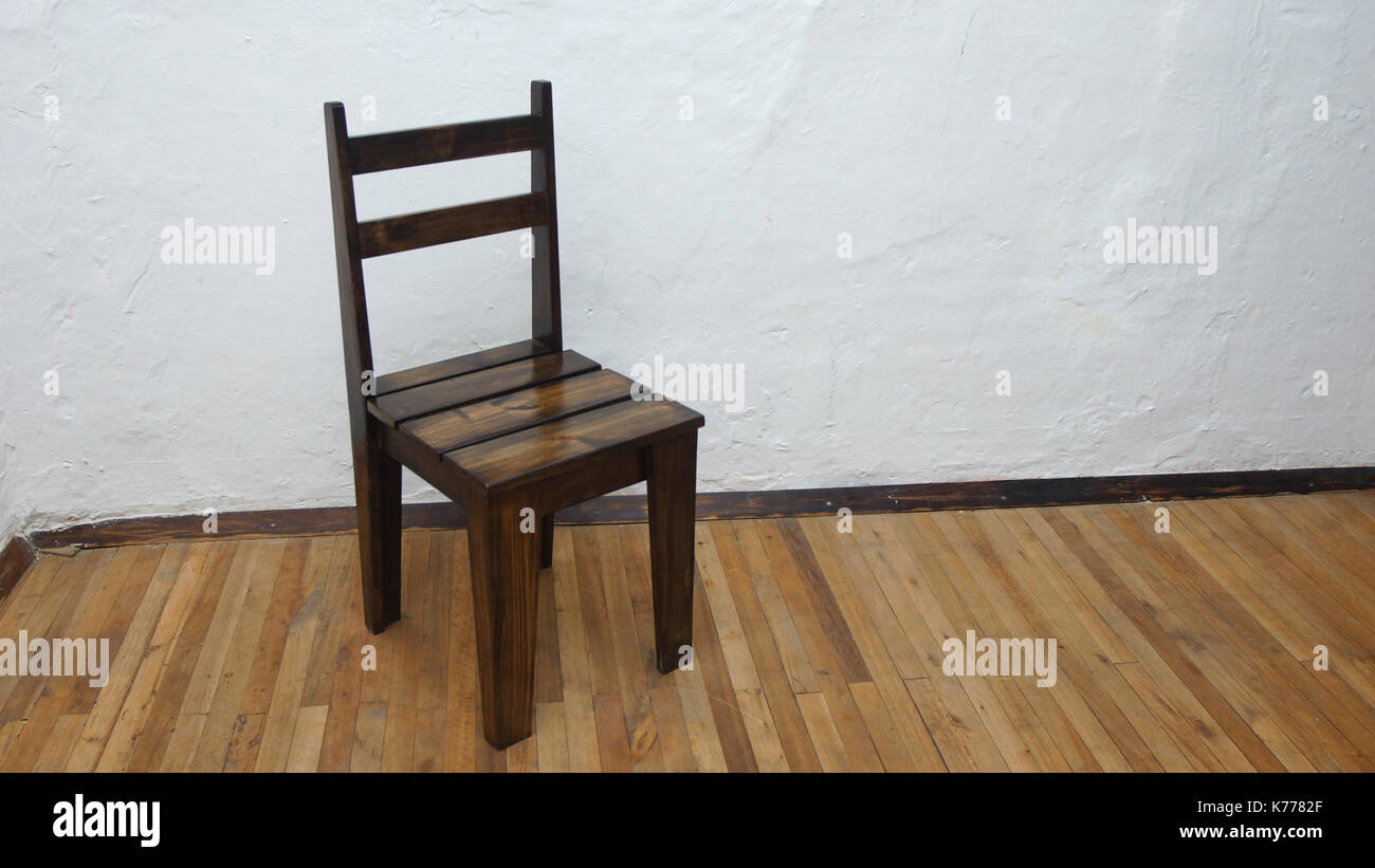 Sedia rustica in legno su un pavimento in legno con parete bianca sullo sfondo Foto Stock