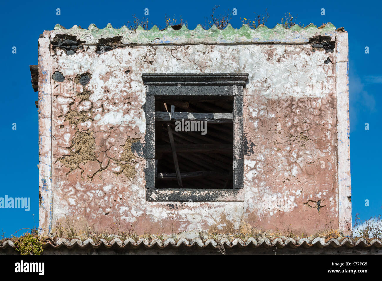 Parte di una casa abbandonata a Sao Miguel Island, isole Azzorre, il Portogallo, la forma di un francobollo. Apre la finestra vuota. Blue sky. Foto Stock