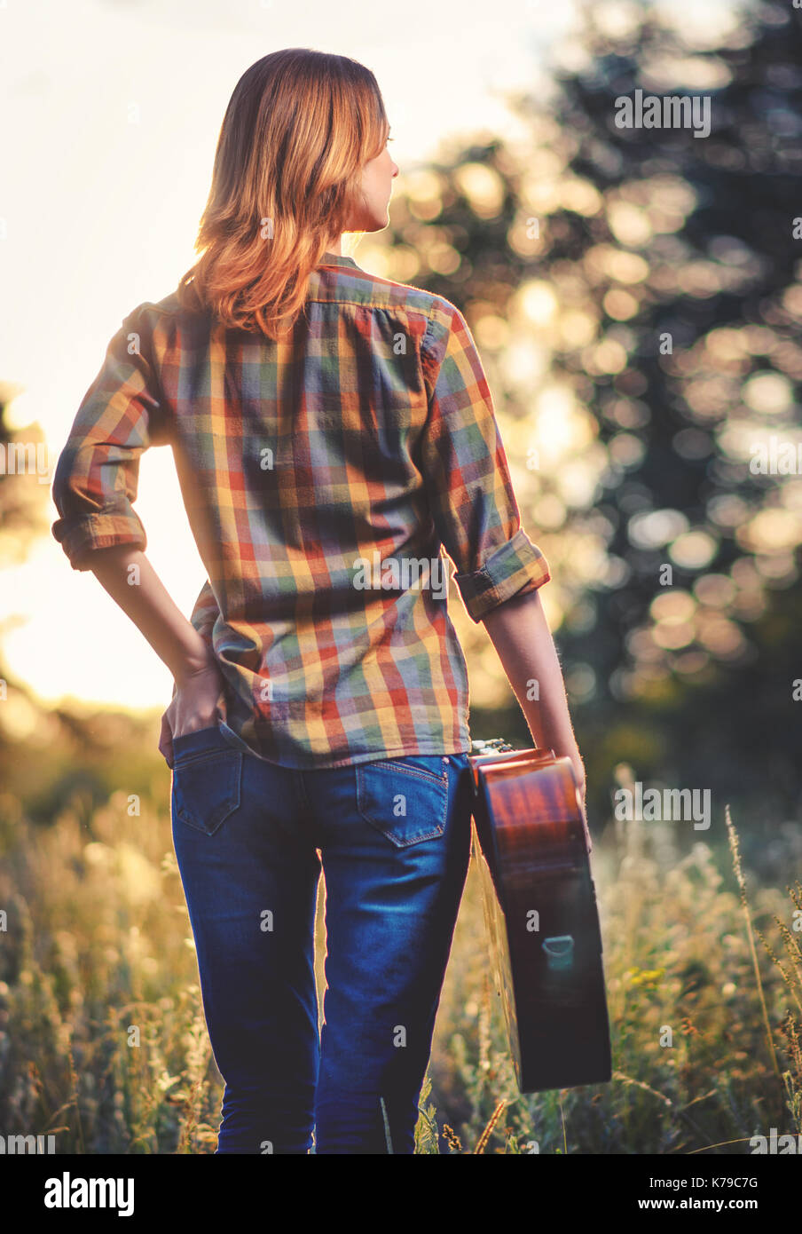 Ragazza con una chitarra nelle sue mani all'aria aperta di autunno, affonda nel fianco. Foto Stock