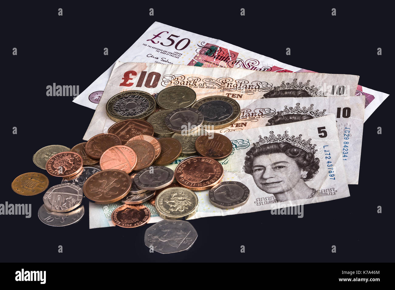 British banconote e monete su uno sfondo nero. Foto Stock