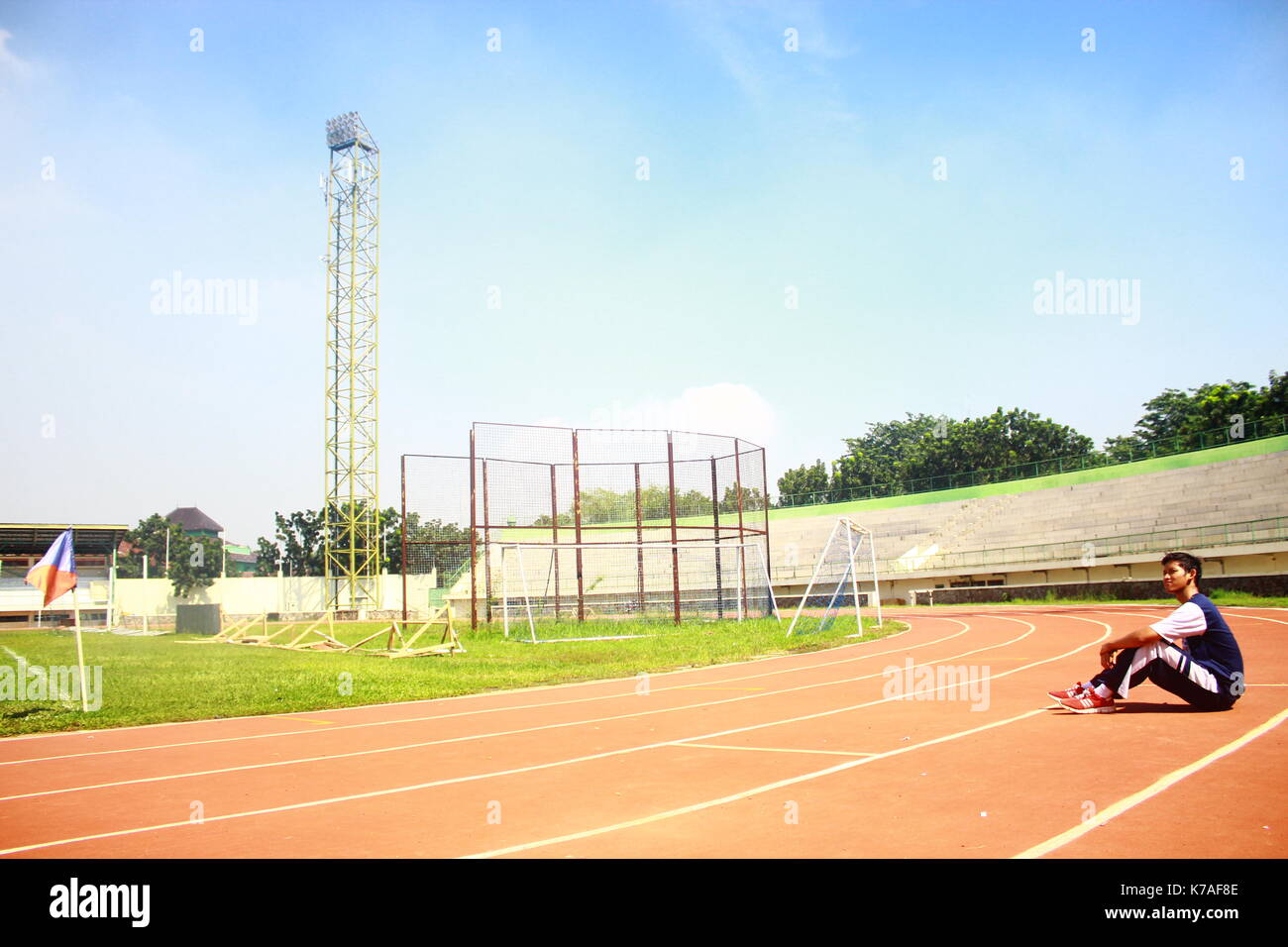 Un runner adolescenti in appoggio al campo dopo la volata, esausto. shot originariamente avuto luogo a singaperbangsa karawang, INDONESIA Foto Stock