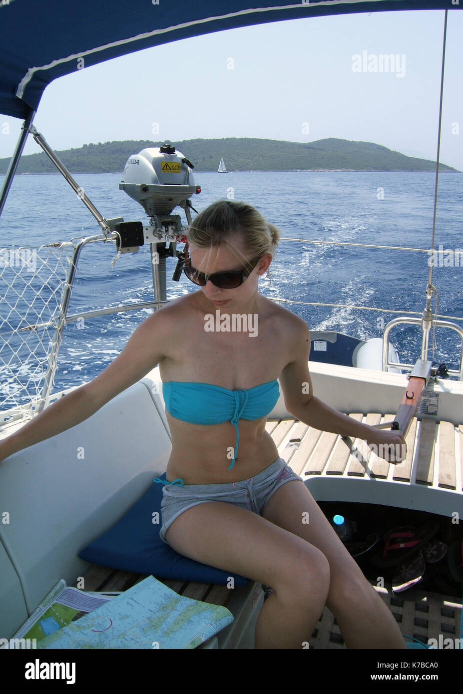 Giovane donna grafico di lettura mentre la vela con una singola mano nelle isole greche Foto Stock