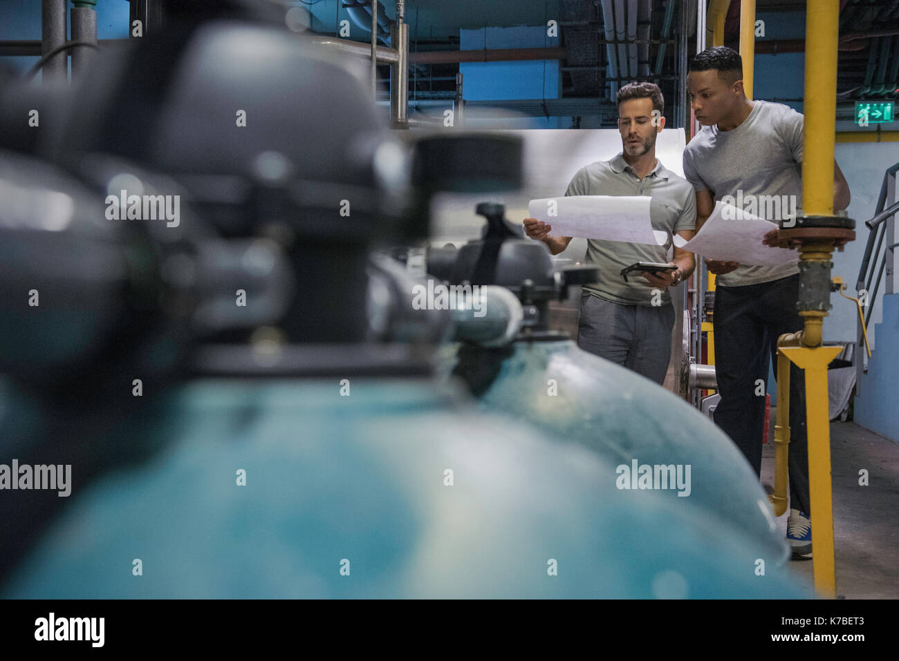 Gli uomini guardando blueprint in ambiente industriale Foto Stock