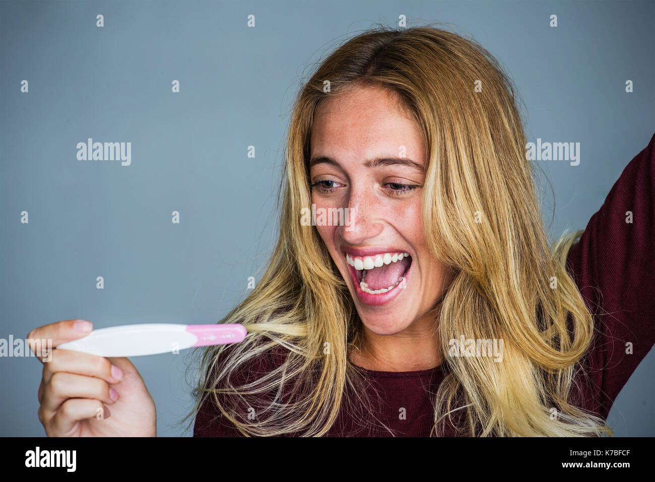 Giovane donna che celebra i risultati di test di gravidanza Foto Stock