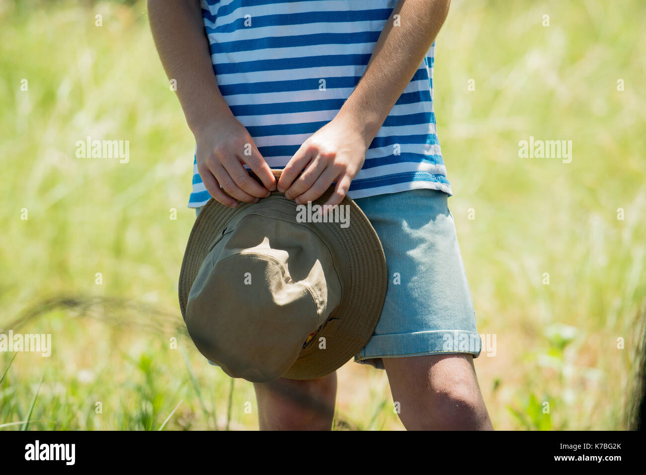 Bambino tenendo la benna hat all'aperto, ritagliato Foto Stock