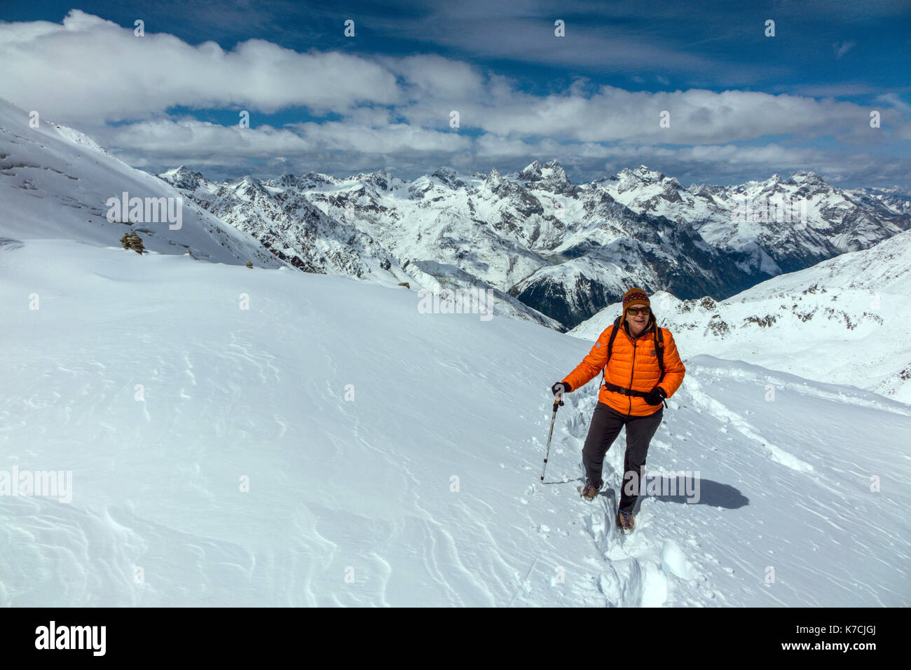 Femmina camminatore di montagna su neve indossando arancione Giacca Piumino Foto Stock