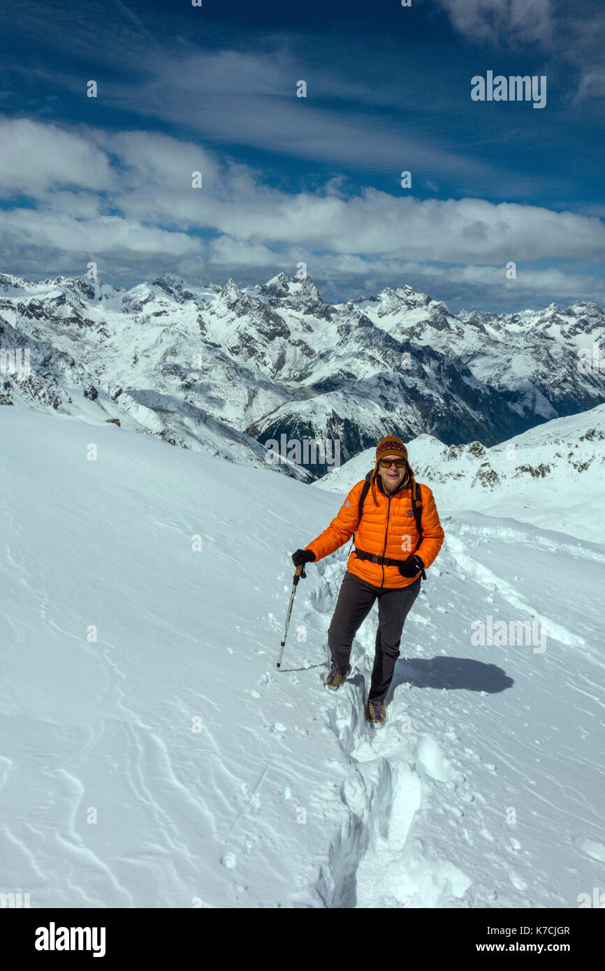 Femmina camminatore di montagna su neve indossando arancione Giacca Piumino Foto Stock