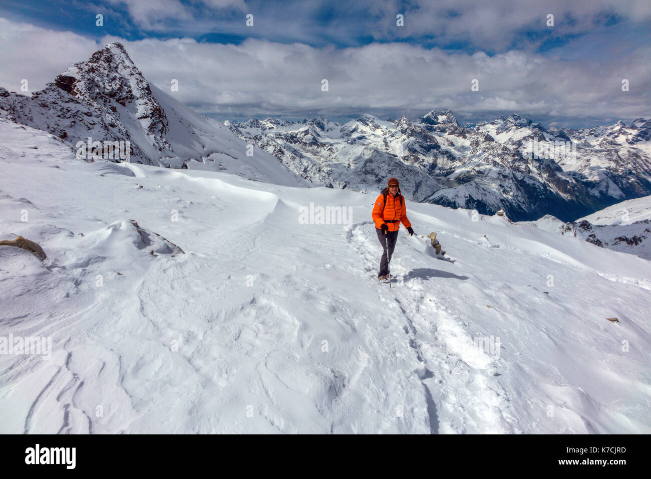 Femmina camminatore di montagna su neve indossando arancione Giacca Piumino Foto Stock