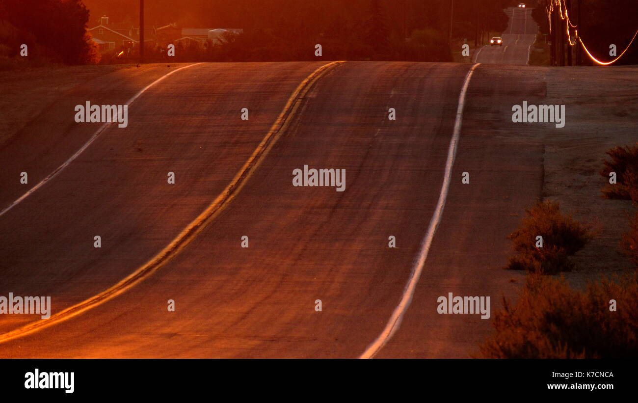 Curva desert highway road che va pensato il Southern California golden state al tramonto con una linea telefonica glinting con oro Foto Stock