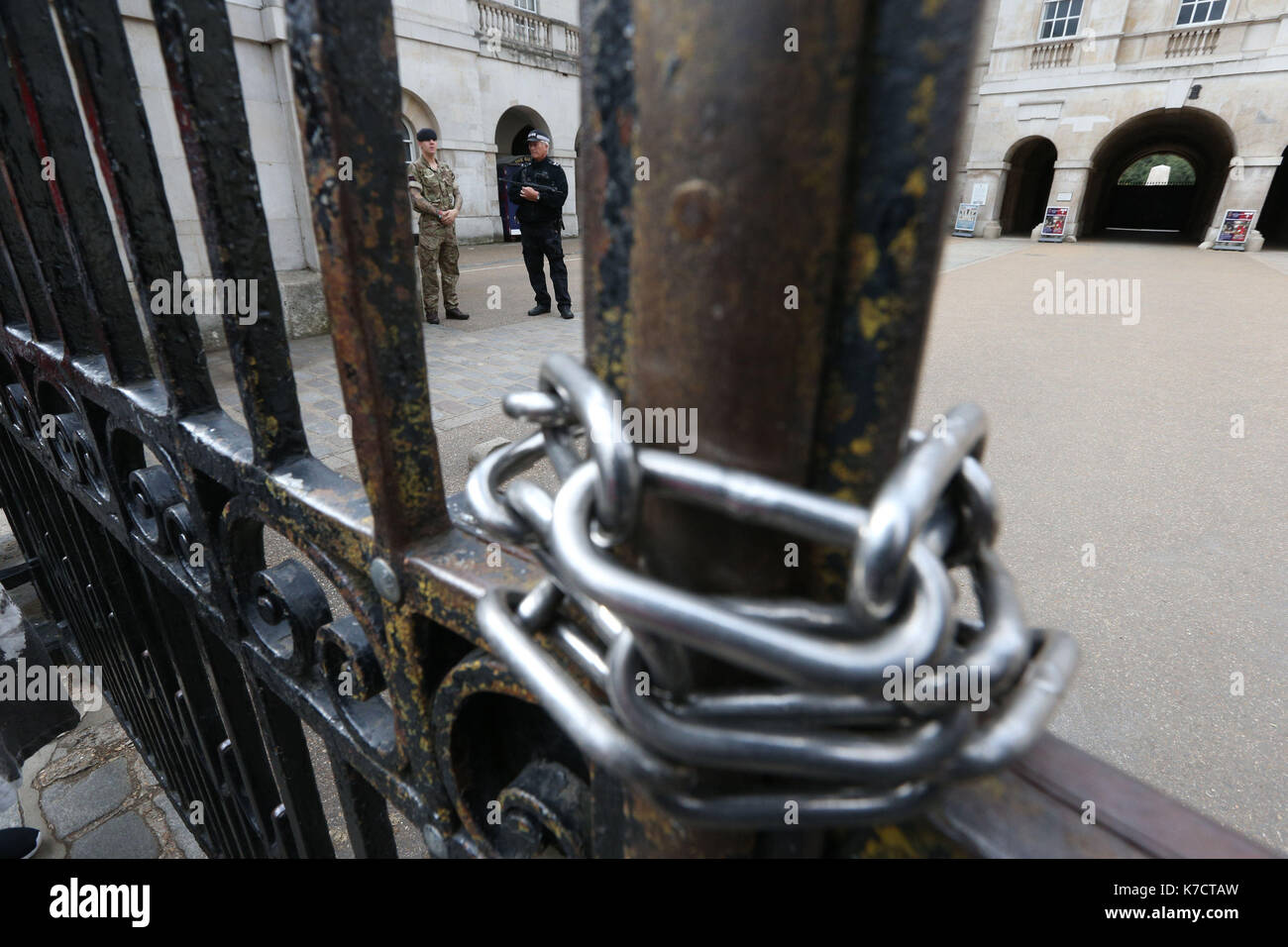 Un agente di polizia armato e soldato dietro cancelli bloccati all'ingresso delle Guardie a Cavallo in whitehall, Londra centrale, come operazione temperer è emanata dopo che gli esperti di sicurezza ha avvertito un altro attacco terroristico potrebbe essere imminente. Foto Stock