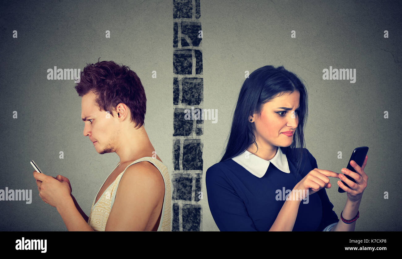 Arrabbiato giovane premuroso sconvolto l uomo e la donna separati dalla parete degustazione di ogni altro sul telefono cellulare Foto Stock