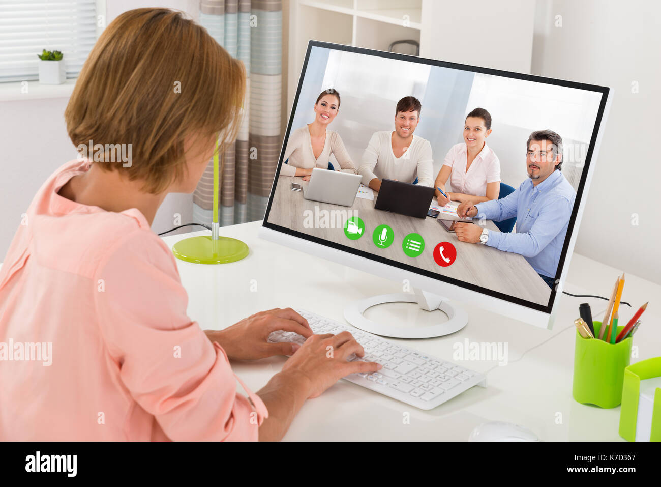Giovane donna la videoconferenza con i colleghi sul computer alla reception Foto Stock