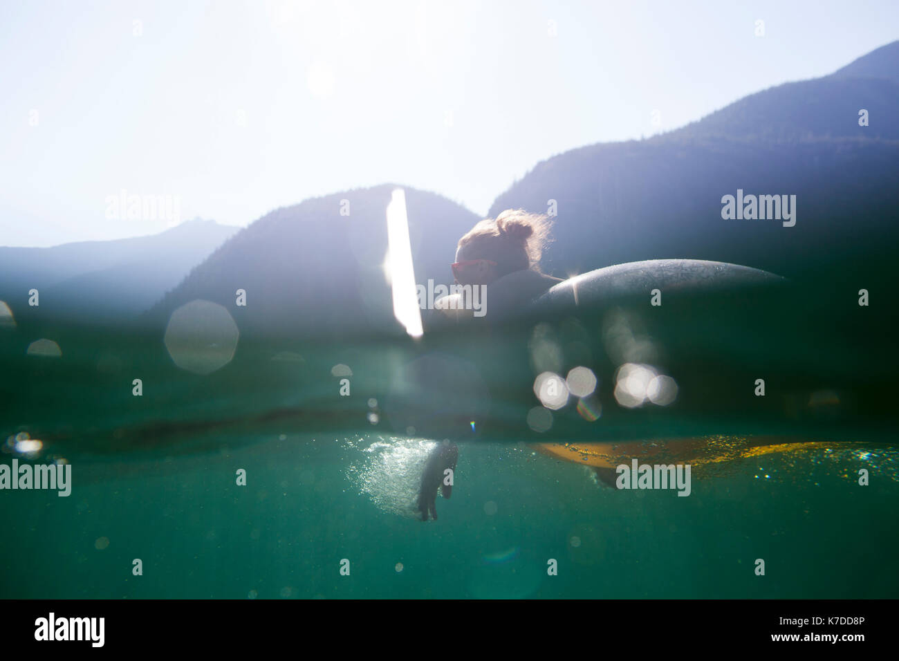 Donna sdraiata sulla zattera piscina nel lago contro le montagne durante la stagione estiva Foto Stock