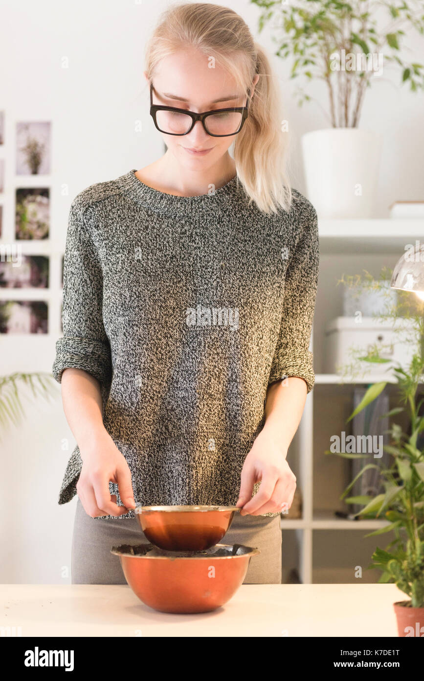 Creative imprenditrice ponendo la ciotola in contenitore metallico per rendere concreta pot Foto Stock