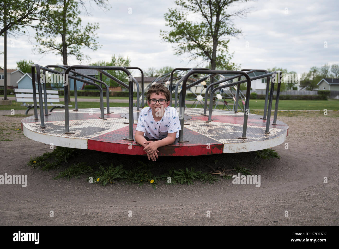 Ritratto di ragazzo disteso sul merry-go-round al parco giochi Foto Stock