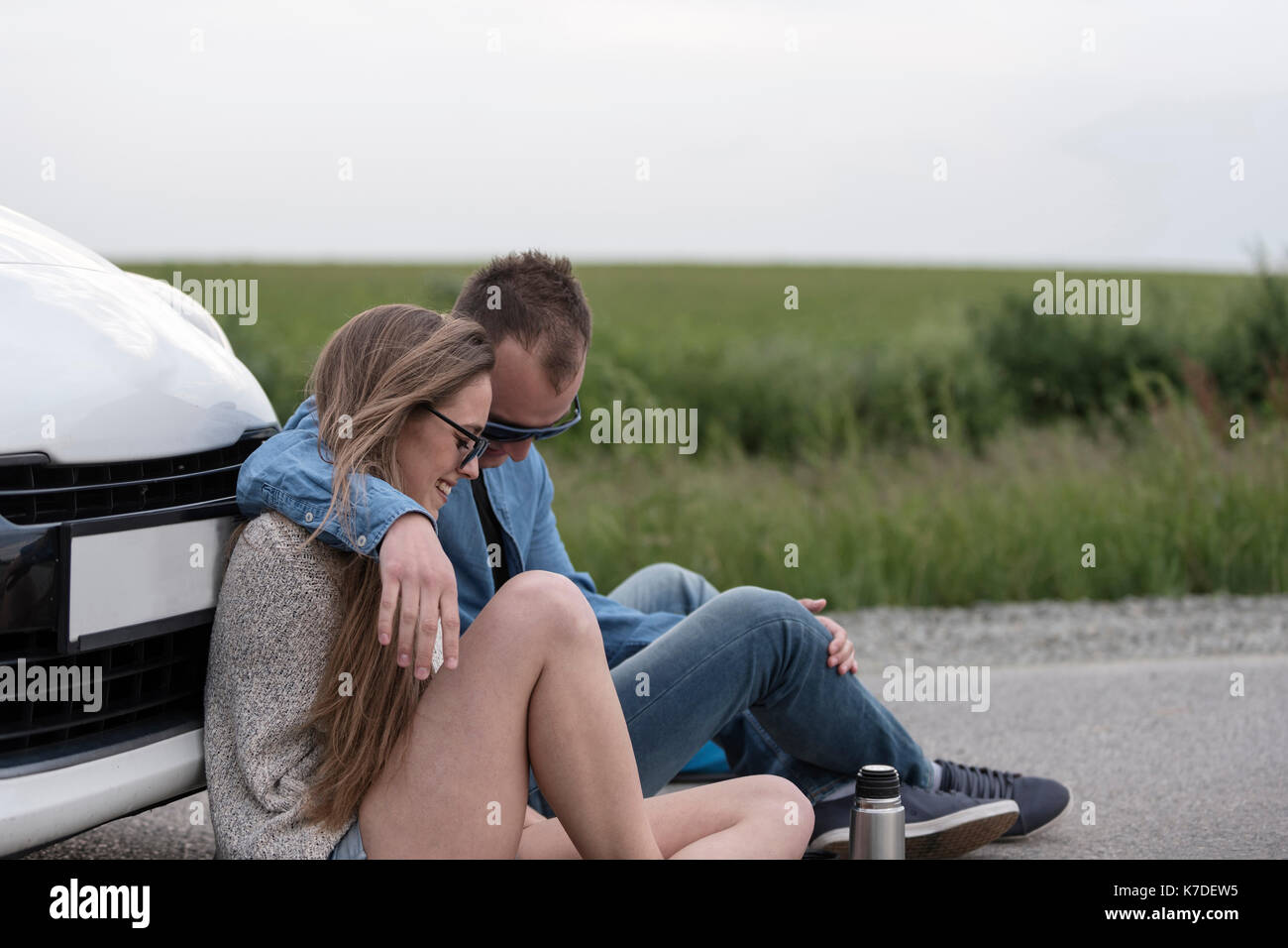 Coppia romantica seduti in auto sulla strada di campagna contro sky Foto Stock