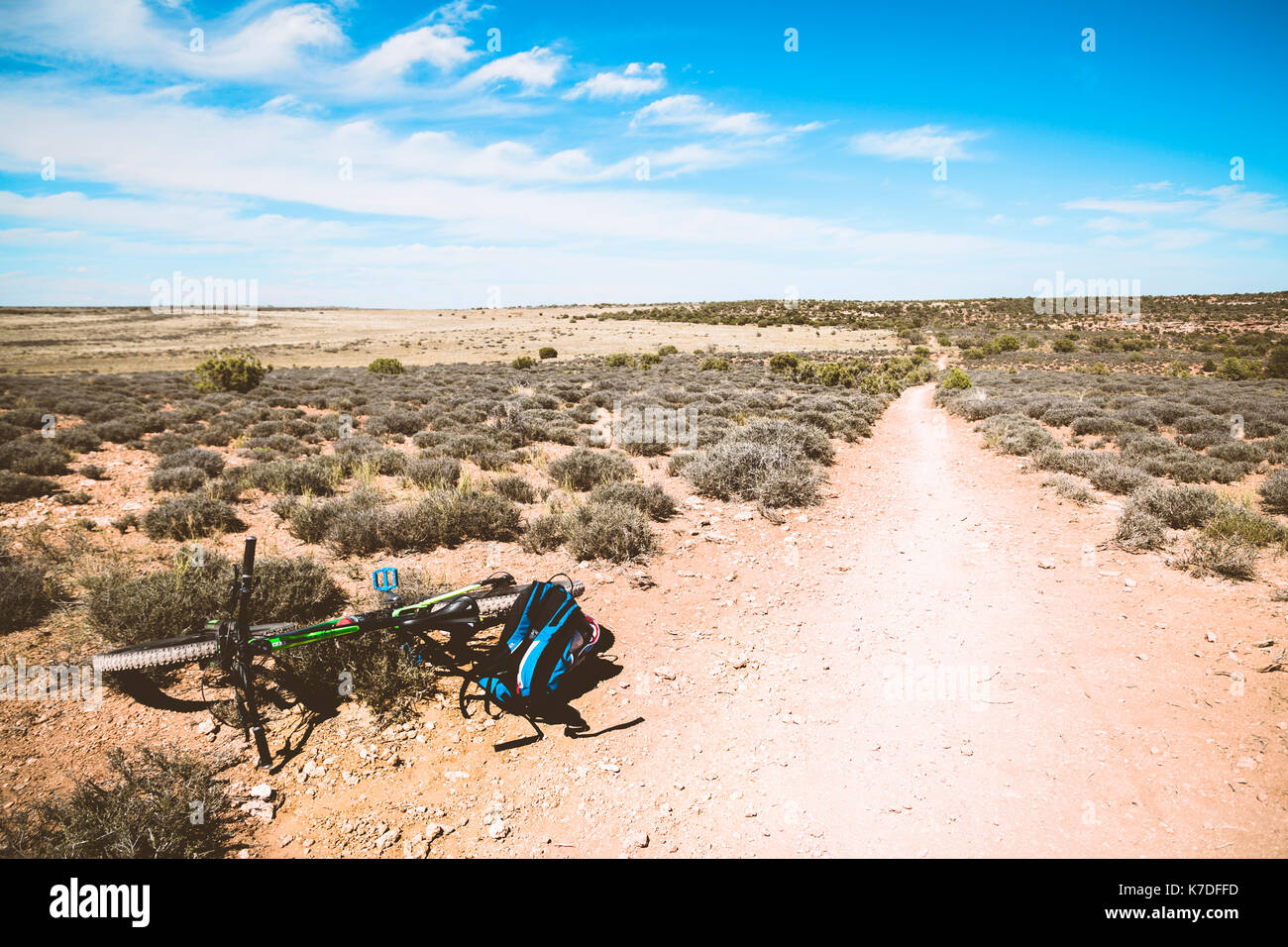 Bicicletta e zaino su semi-arido paesaggio contro sky Foto Stock